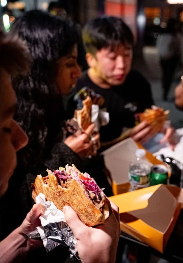 A customer eating a döner standing at a counter