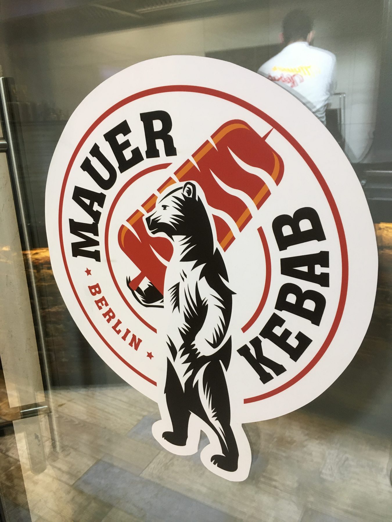 Mauer Kebab window logo with a worker visible inside the shop at night