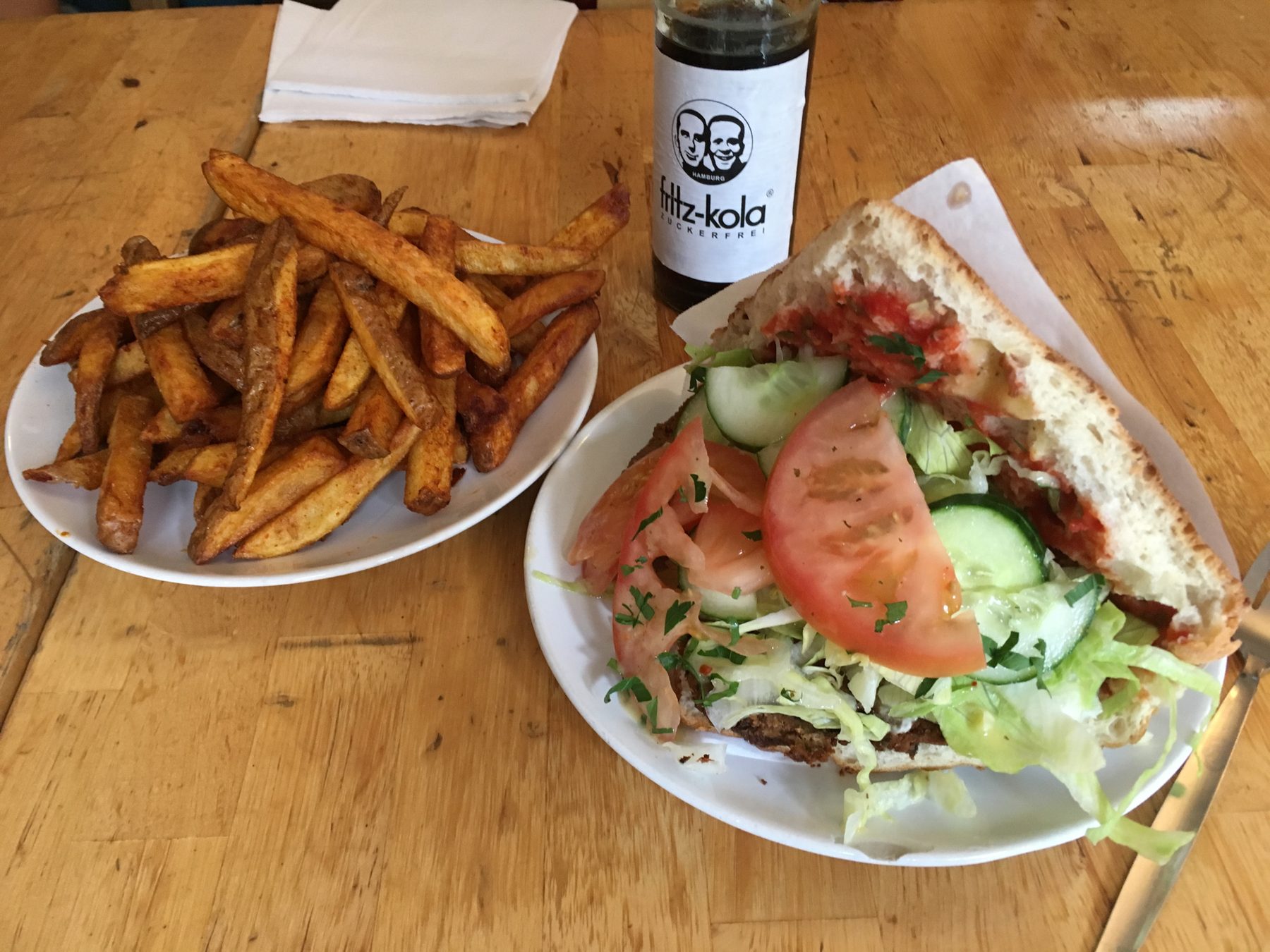 Vegan döner sandwich with browned plant-based slices, shredded vegetables, herbs, and creamy sauce in flatbread