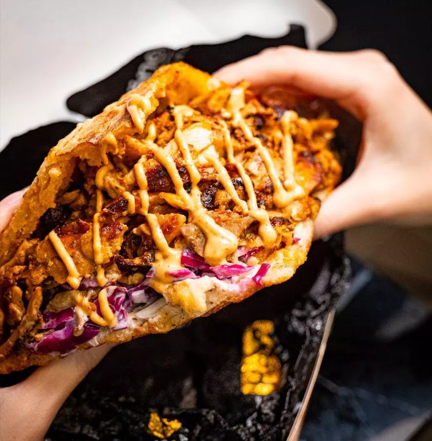 A stuffed German döner in toasted triangular bread with cabbage, garlic sauce and chili